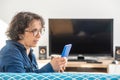 Cheerful brunette senior woman using smartphone while sitting on sofa Royalty Free Stock Photo