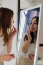 Cheerful brunette woman applying lipstick balm on lips in front of mirror makeup beauty care Royalty Free Stock Photo