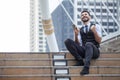 Cheerful Business Man Celebrating Success with mobile phone sitting on the stairs in urban city outdoors, looking up , good news, Royalty Free Stock Photo