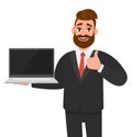 Cheerful business man holding or showing a latest new brand laptop computer PC and gesturing, making thumbs up sign with hand