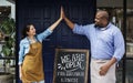 Cheerful business owners standing with open blackboard Royalty Free Stock Photo