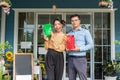 Cheerful business owners standing welcomingly together in front of the counter of their cafe