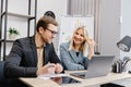 Cheerful business people using a laptop in an office. Young entrepreneurs smiling while working together in a modern workspace. Royalty Free Stock Photo