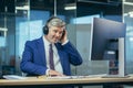 Businessman on a break listening to music and dancing with big headphones, senior and experienced gray-haired man working Royalty Free Stock Photo