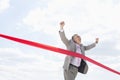 Cheerful businessman crossing finish line against sky Royalty Free Stock Photo