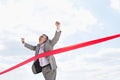 Cheerful businessman crossing finish line against sky Royalty Free Stock Photo