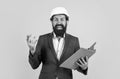 cheerful businessman in helmet looking at new drawings and making notes, builder work Royalty Free Stock Photo