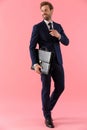Cheerful businessman holding a briefcase and adjusting his tie