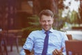 Cheerful businessman sitting on chair at sidewalk cafe