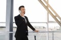 Cheerful businessman standing in airport, talking on phone Royalty Free Stock Photo