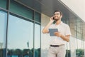 Cheerful businessman using phone and tablet outdoors Royalty Free Stock Photo