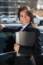 Cheerful businesswoman with folder near black car Royalty Free Stock Photo