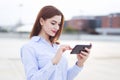 Cheerful businesswoman messaging on smartphone and smiling at outdoors