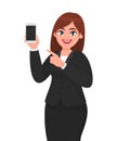 Cheerful businesswoman showing blank screen mobile, cell or smart phone and pointing hand finger towards. Mobile phone technology.