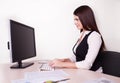 Cheerful businesswoman working at her desk looking at camera in Royalty Free Stock Photo