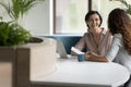 Cheerful businesswomen discuss paperwork, contract details at workplace