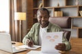 Cheerful busy middle aged black guy makes notes and works with graphs and charts, analysis financial data