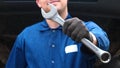 A cheerful car repairman on the street repairs the engine and lower part of the car, shows different emotions, dances with a big w Royalty Free Stock Photo