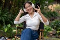 A cheerful and carefree Asian woman is enjoying the music on her headphones while sitting outdoors Royalty Free Stock Photo