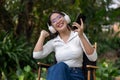 A cheerful and carefree Asian woman is enjoying the music on her headphones while sitting outdoors Royalty Free Stock Photo