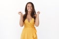 Cheerful carefree attractive brunette woman in yellow dress, grinning joyfully, squinting and smiling toothy