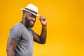 Cheerful carefree young dark-skinned african american man with trendy hat smiling, posing isolated against yellow wall with copy Royalty Free Stock Photo