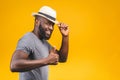 Cheerful carefree young dark-skinned african american man with trendy hat smiling, posing isolated against yellow wall with copy Royalty Free Stock Photo