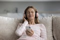 Cheerful woman in big wireless pink headphones holding smartphone
