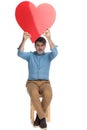 Cheerful casual man holding a heart shape above his head Royalty Free Stock Photo