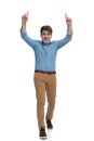 Cheerful casual man pointing up with both hands