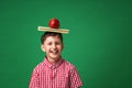 Cheerful Caucasian boy holds his school books and a green Apple on his head Royalty Free Stock Photo