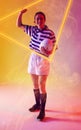 Cheerful caucasian female rugby player with ball raising hand by illuminated triangle