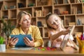 Cheerful caucasian girl studying alphabet with professional tutor, positive female teacher helping kid and taking notes Royalty Free Stock Photo