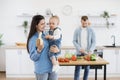 Mother proposing banana to child while father cooking lunch