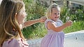 Cheerful caucasian mother and young daughter sitting together on a park bench, holding a flower, exuding joy and confidence Royalty Free Stock Photo