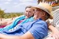 Cheerful caucasian senior couple talking and lying on hammock at beach during sunny day Royalty Free Stock Photo