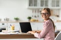 Cheerful caucasian teen schoolgirl in glasses look at camera at table with computer with blank screen Royalty Free Stock Photo