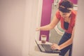 Cheerful caucasian young beautiful woman use laptop computer waiting at the laundrette for clean clothes - concep tof urban city Royalty Free Stock Photo