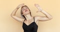 Cheerful caucasian young woman grimacing, fooling and dance around on beige background. Humor concept