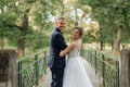 Cheerful, chancy young married couple of man and woman in glasses standing together on bridge in park, holding hands Royalty Free Stock Photo