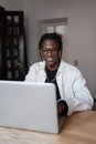 Cheerful charismatic African American man freelancer typing text on laptop keyboard sits at table