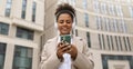 cheerful charismatic african american woman listening to music in headphones with a mobile phone in her hands outside Royalty Free Stock Photo