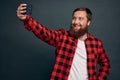 Cheerful and charismatic european guy with beard talking to friend via internet messanger app, holding smartphone raised hand,