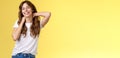 Cheerful charismatic good-looking curly-haired woman stretching posing yellow background touch neck flirty smiling