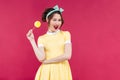 Cheerful charming pinup girl with yellow lollipop standing and w