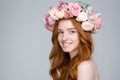 Cheerful charming woman in flower wreath over grey background