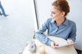 Cheerful charming young woman using tablet in cafe