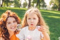 Cheerful child blowing soap bubbles in the park with woman looking at the camera Royalty Free Stock Photo