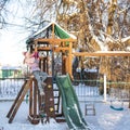 A cheerful child girl plays on the Playground on snowy winter day Royalty Free Stock Photo