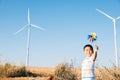 Boy's playful fascination near wind turbines holding a pinwheel toy Royalty Free Stock Photo